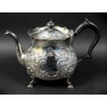 A Victorian silver teapot, repousse decorated with flowers and C scrolls in rococo style, ebonised