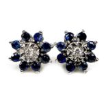A pair of white gold, sapphire and diamond flowerhead rings, formed of royal blue sapphires with