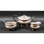 An George V silver three piece tea service, with faceted bodies and fruiting vine cast rims,