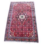 A Hamadan rug, caucasian medallion on red ground with floral design, and dark blue ground borders,