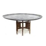 A Middle Eastern copper charger table, the large circular surface engraved with Islamic motifs, on a