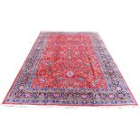 A Sarough rug, with floral design across central red ground and dark blue ground borders, 350 by