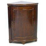 A 19th century mahogany corner cupboard, with single curved panel door enclosing two shaped shelves,