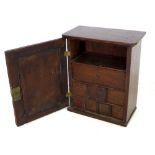 An oak table top cabinet, single panel door opening to reveal a shelf and eight fitted trinket