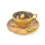 A Royal Worcester tea cup and saucer, painted with fruit to a mossy ground, the cup painted on the