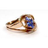 A gold dress ring in the form of a flower, set with four small cornflower blue sapphires, marks