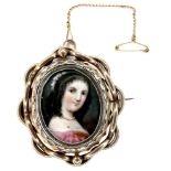 An early 19th century gold framed portrait miniature brooch, depicting a girl in a pink dress,
