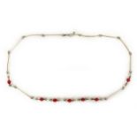 An early 20th century yellow metal necklace with faceted red glass beads and round milk glass beads,