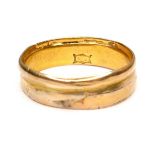A gold wedding band ring, formed from two separate thinner rings joined together, marks partially