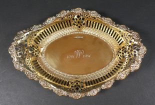 An Edwardian silver gilt commemorative bowl, of boat form with pierced sides and repousse scrolls to