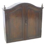 An 18th century oak cupboard, with arched moulded cornice, turned finials, two doors enclosing two