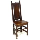 A 17th century oak side chair, with scroll finials and solid seat, raised on turned supports with