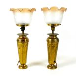 A pair of Art Nouveau brass table lamp bases, with embossed floral decoration, frosted glass