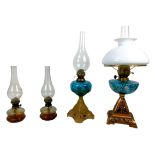 A group of four early 20th century oil lamps, the largest with hand painted font, milk glass