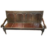 A George III oak settle, with four fielded panels, open shaped arms, replacement seat, raised on