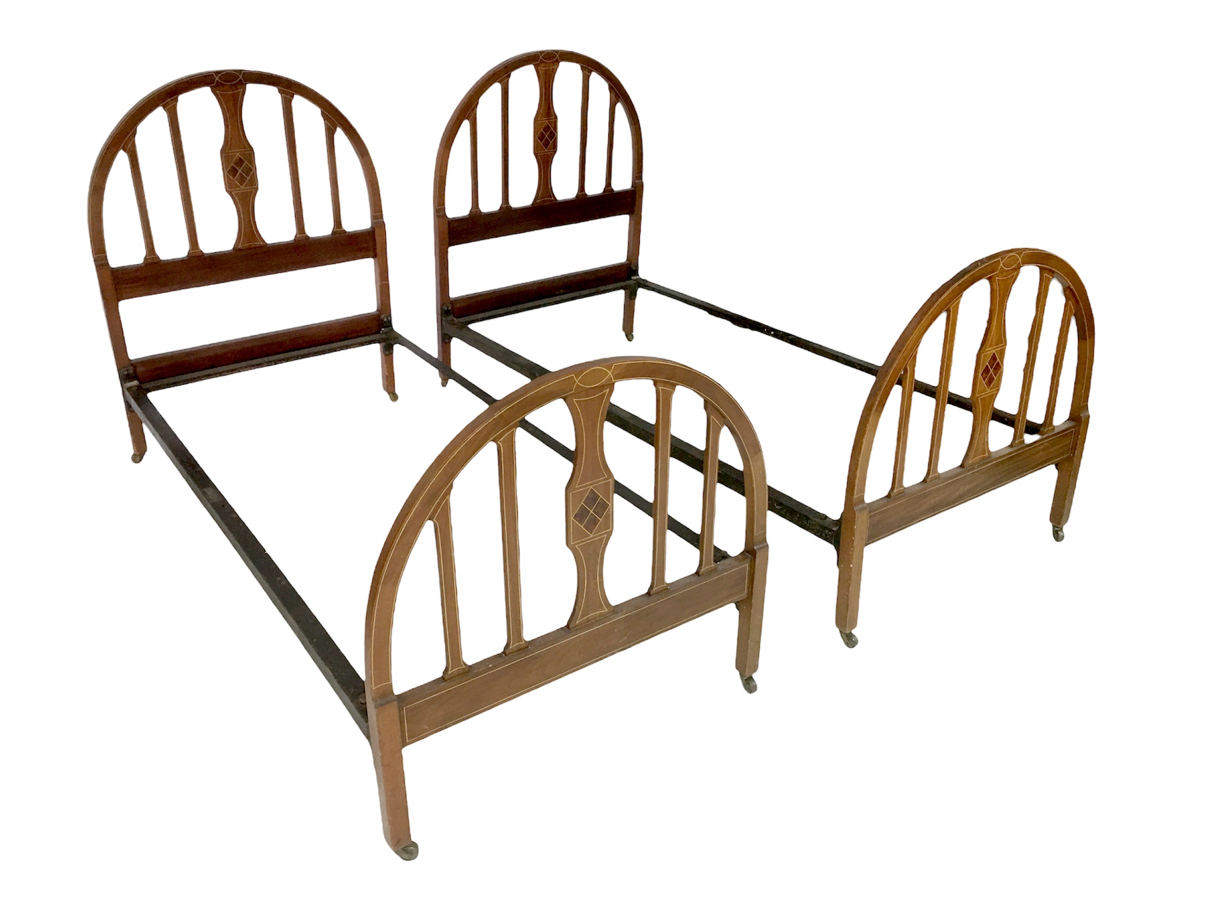 A pair of Edwardian single beds, with mahogany bed ends and VONO cast iron stretchers, each bed 92