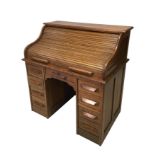 An Edwardian oak roll top desk, fitted with an arrangement of small drawers and pigeon holes