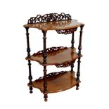 An early 20th century three tiered walnut whatnot, with pierced foliate decoration, turned