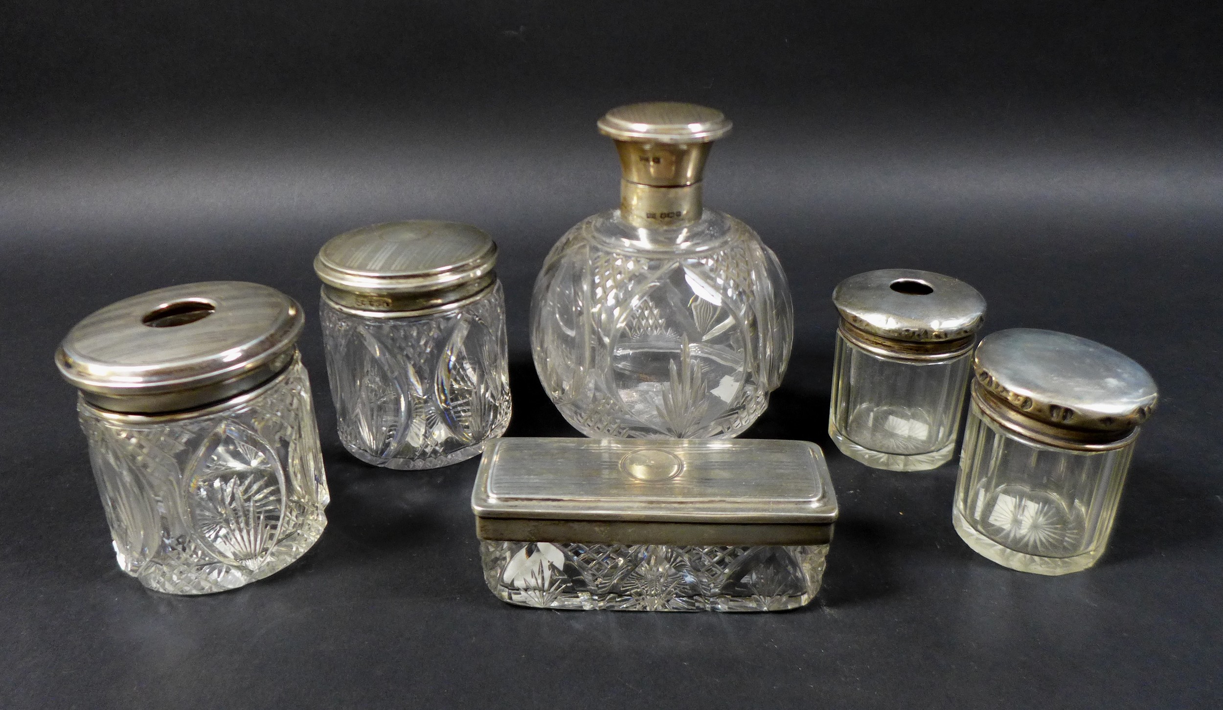 A collection of silver lidded cut glass dressing table jars, including a four piece set by