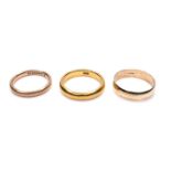 A group of three yellow gold wedding band rings, comprising one with marks obscured but tests as