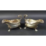 A pair of Edwardian silver gravy boats, with a gadrooned rim and scroll handles, each raised on