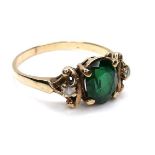 An Edwardian gold ring, the principle oval cut green paste stone, 8mm high, flanked by two small