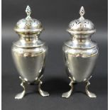 Two Edwardian condiments, both with flame finials, raised upon tripod bases with pad feet, with
