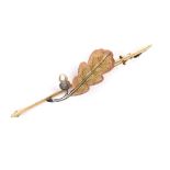 An Edwardian 15 and 18ct gold bar brooch, formed as a single oak leaf with rose gold edging, and