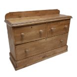 A pine chest of two short over one long drawer, with turned handles, upstand to top, plinth base,