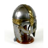 A replica metal steel and brass helmet, with cheek plates, hinged ear flaps, and chain mail neck