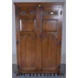 AN EARLY 20TH CENTURY ARTS AND CRAFTS OAK TWO DOOR ARMOIRE