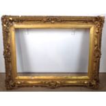 A LARGE ORNATE PLASTER GILT SWEPT FRAME