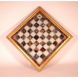 A 19TH CENTURY REVERSE PAINTED GLASS CHESS BOARD, IN A GILT WOOD FRAME