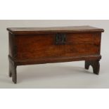 A MINIATURE 18TH CENTURY ELM COFFER ON SILHOUETTE SLAB ENDS