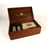 A WALNUT HUMIDOR CONTAINING CIGARS AND CIGAR CUTTERS