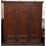 A 20TH CENTURY WALNUT PANELLED AND CARVED THREE DOOR BOOKCASE