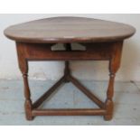 An 18th Century oak cricket table, the circular planked top raised on three baluster turned supports