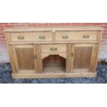 An antique pine sideboard containing 2 short drawers with fancy brass handles, over a single central