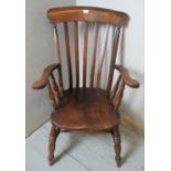 A 19th century elm Windsor fireside armchair raised on ring turned supports united by a waisted