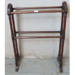 A turn of the century mahogany double towel rail featuring finials, raised on scrolled feet.
