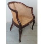 An Edwardian mahogany bergère tub chair, raised on cabriole front supports & outswept rear supports.