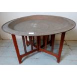 A large early 20th century Benares table, the hand hammered dished copper top depicting an