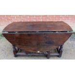 A large 18th Century oak oval gateleg dining table, raised on turned and block supports united by