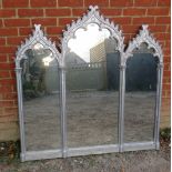 A large ornate triptych over mantle mirror in a silver resin frame with leaf mouldings to cornice.