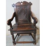 A 17th Century oak wainscot chair, with carved cornice and carved panel back, on turned and block
