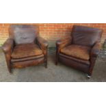A pair of Edwardian club chairs, upholstered in distressed brown leather with brass studs, raised on