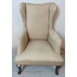 A Georgian wingback armchair, on oak cabriole front supports and tapered rear supports,