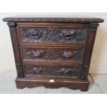 A diminutive 19th century oak chest of three long drawers, ornately carved with fruiting vines in