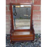 An Edwardian mahogany wall hanging shelf with bevelled mirror back over a lidded compartment with