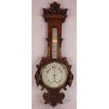 An Edwardian carved oak barometer by T.B Winter & Son, Newcastle Upon Tyne, with deeply carved